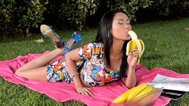 Salacious Asian babe  rubs her clit and eats banana in the garden